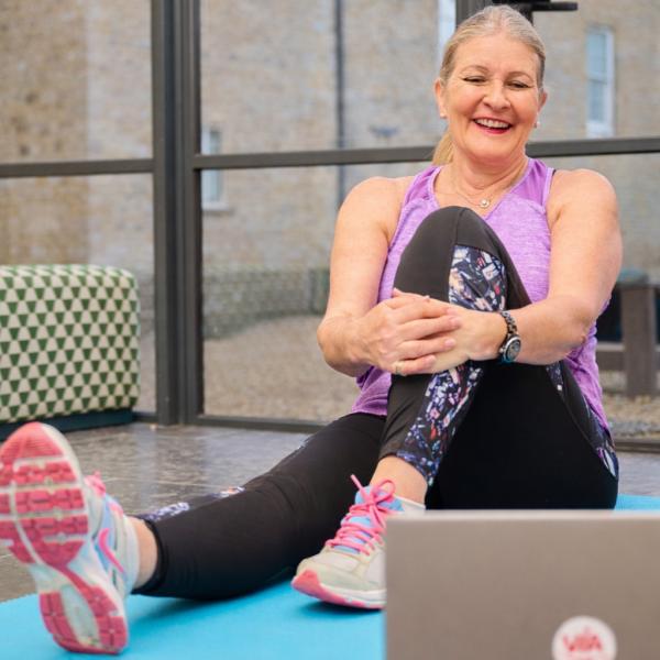 A seated stretch while following an online course on a laptop.